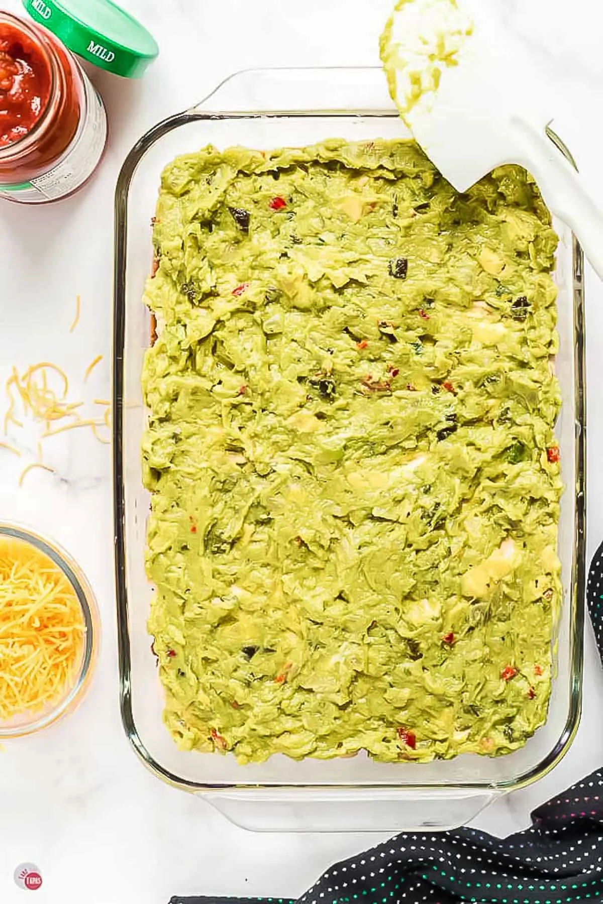 guacamole layered in a clear dish with spatula
