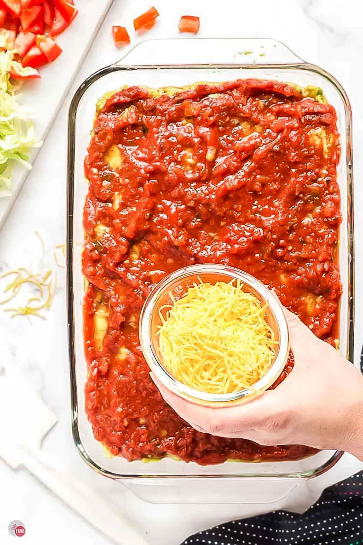 salsa layered in a clear dish with a small bowl of shredded cheese