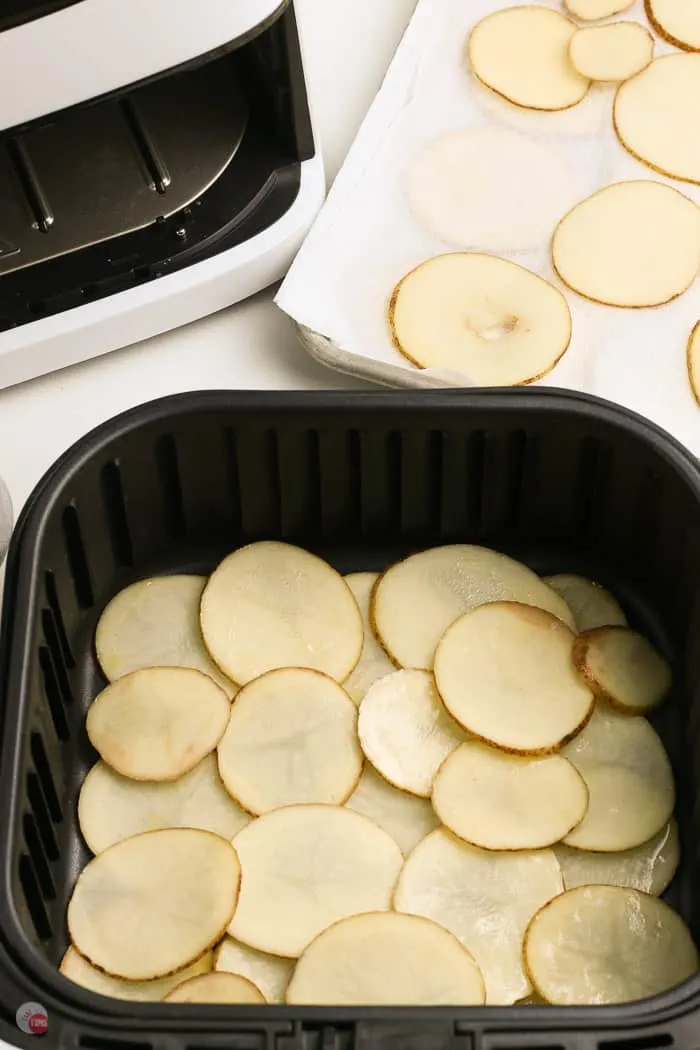 raw potato slices in an air fryer basket