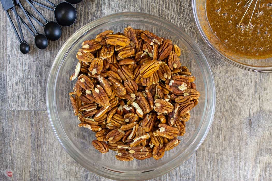 pecans in clear bowl with bowl of sauce and measuring spoons