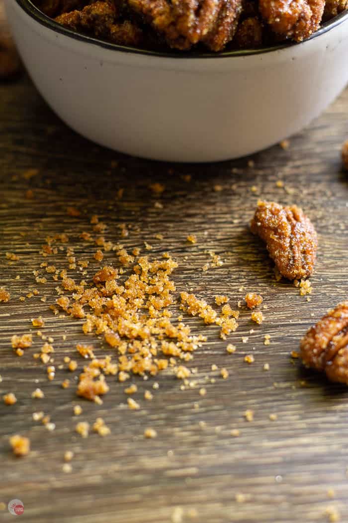 crumbs on a board next to a white bowl and scattered pecans
