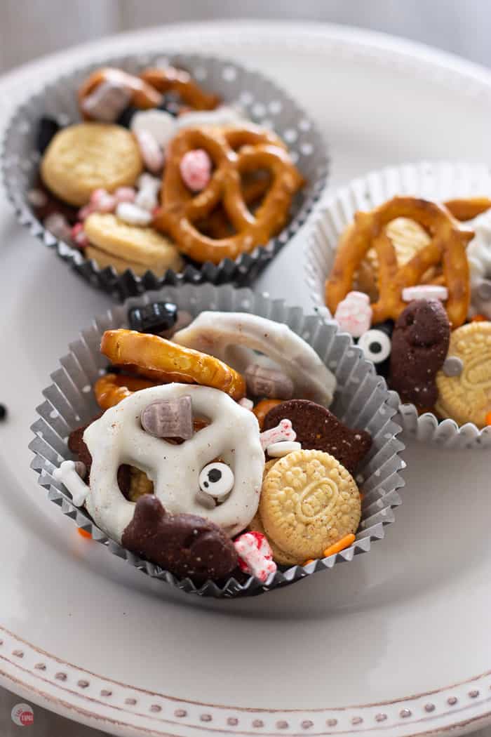 three cupcake liners with Halloween mix in them on a white cake plate
