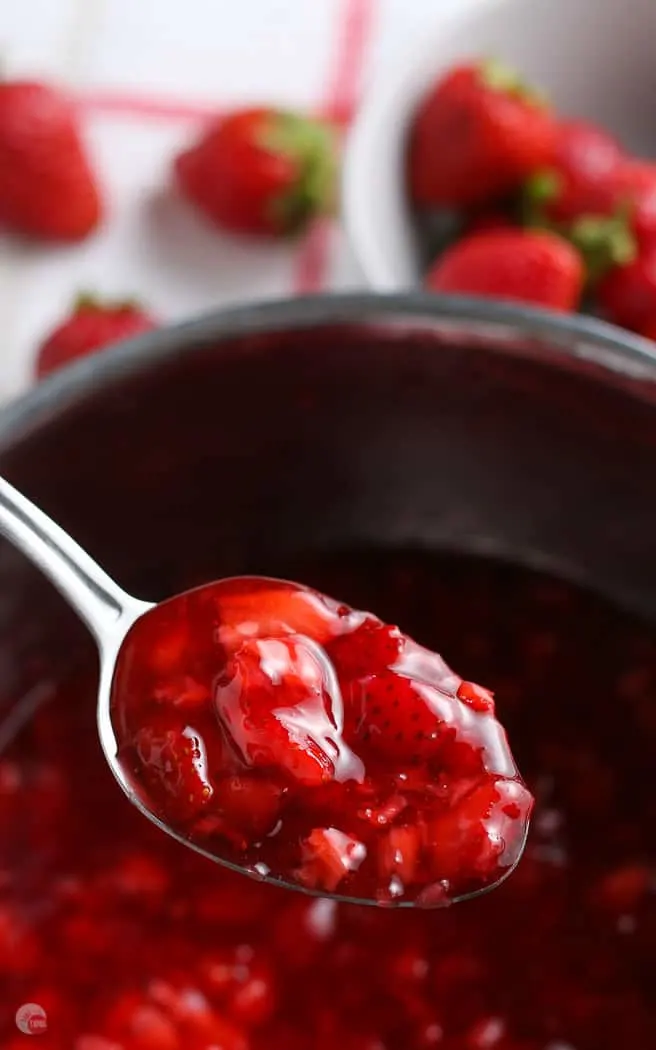 spoon of strawberry compote above a pot