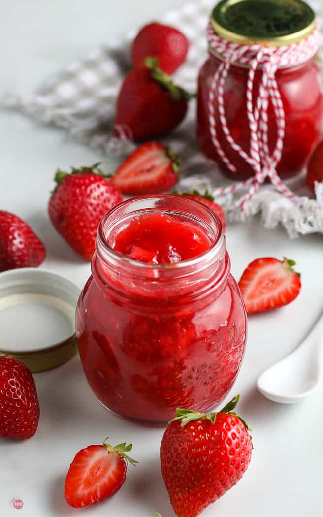 jar of strawberry sauce with fresh berries around it