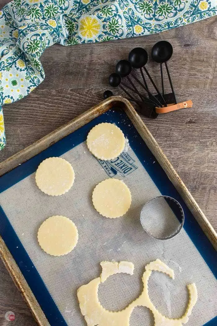 cookie dough cut into rounds on a cookie sheet