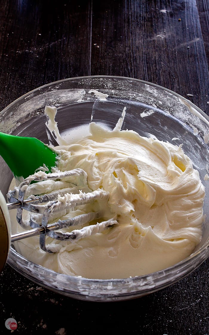 bowl of frosting with green spatula and beaters