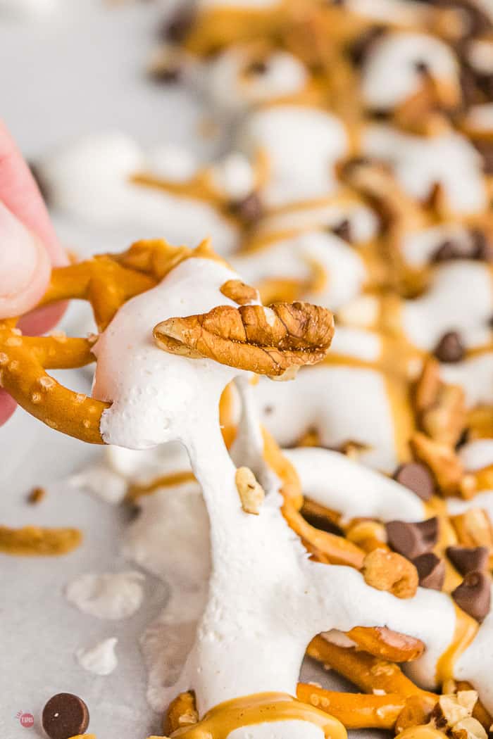 hand pulling a pretzel covered in marshmallow