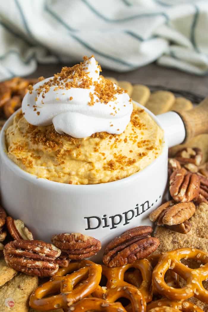 pumpkin dip in a white bowl surrounded by pretzels