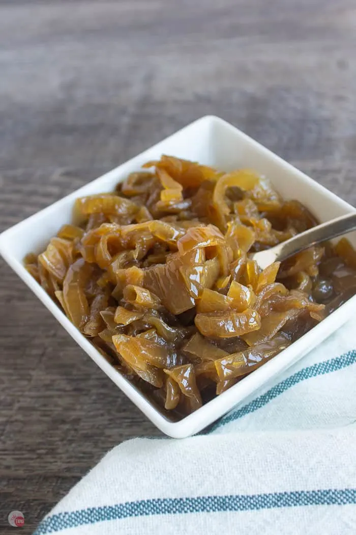 caramelized onions in a white bowl with a fork