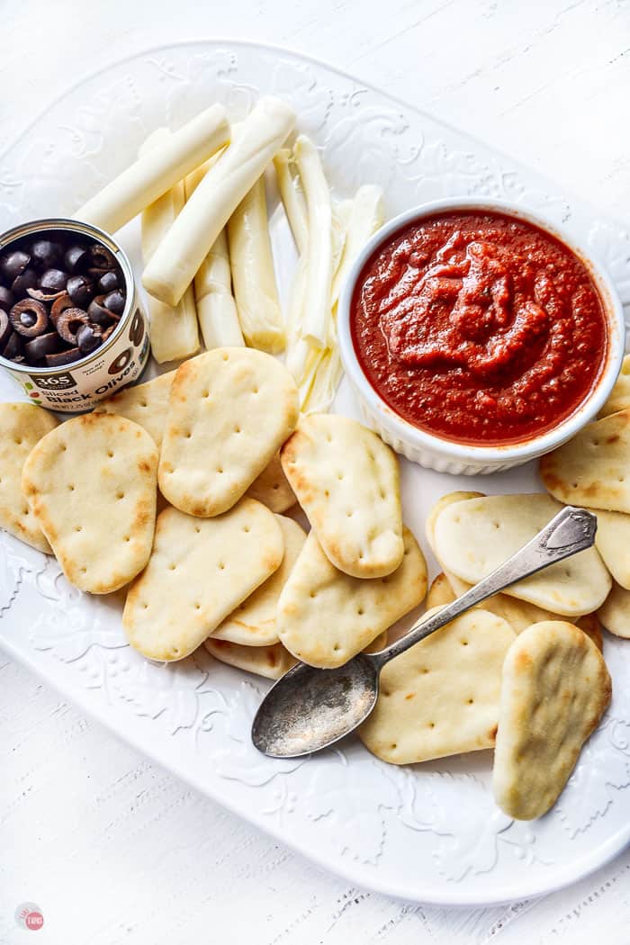 mini naan bread on a white plate with tomato sauce, olives, and cheese