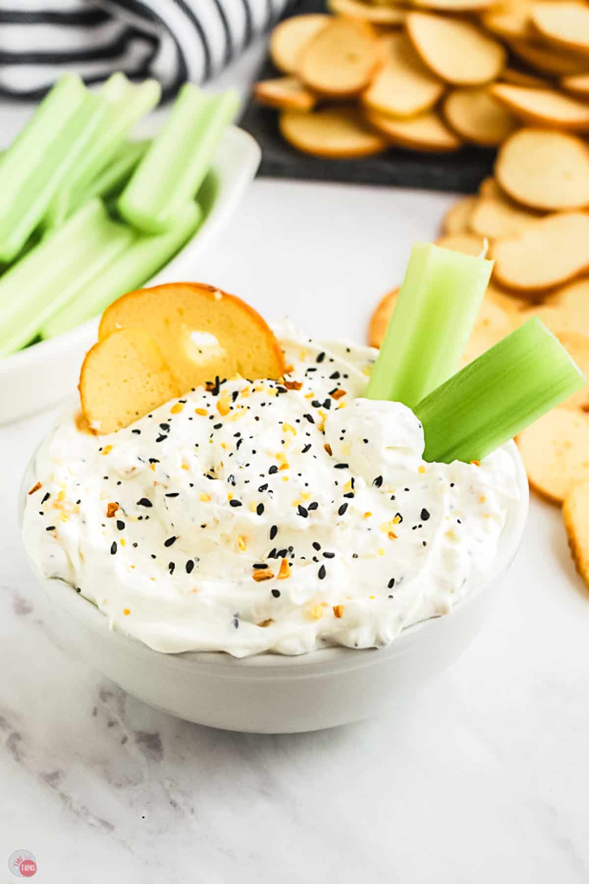 bagel dip in a white bowl with striped towel