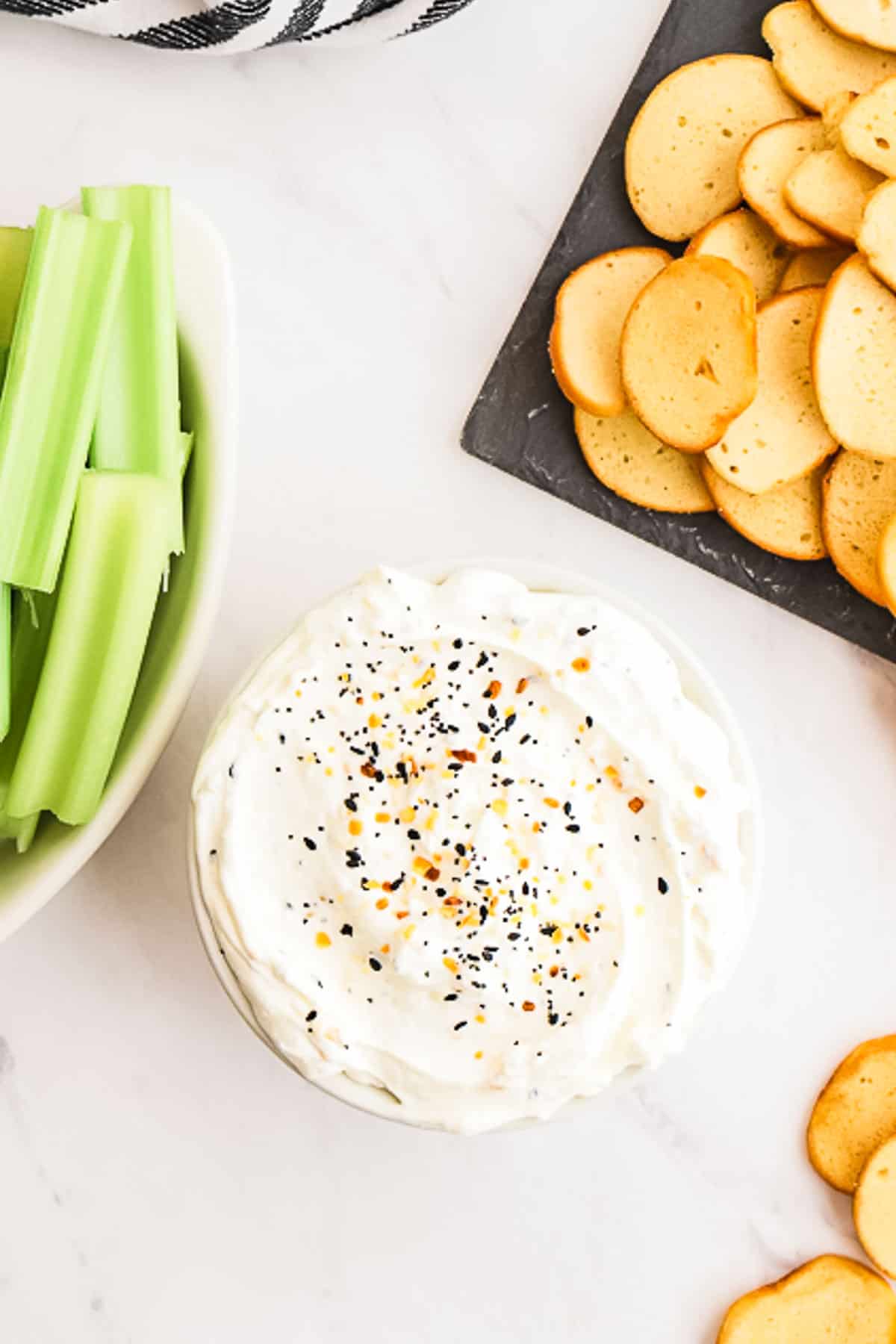 bowl of bagel dip surrounded by celery and bagel chips