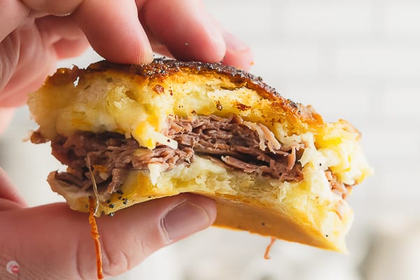 hand holding a sandwich with a bite taken