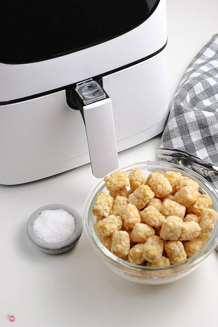 frozen tots in a bowl next to air fryer