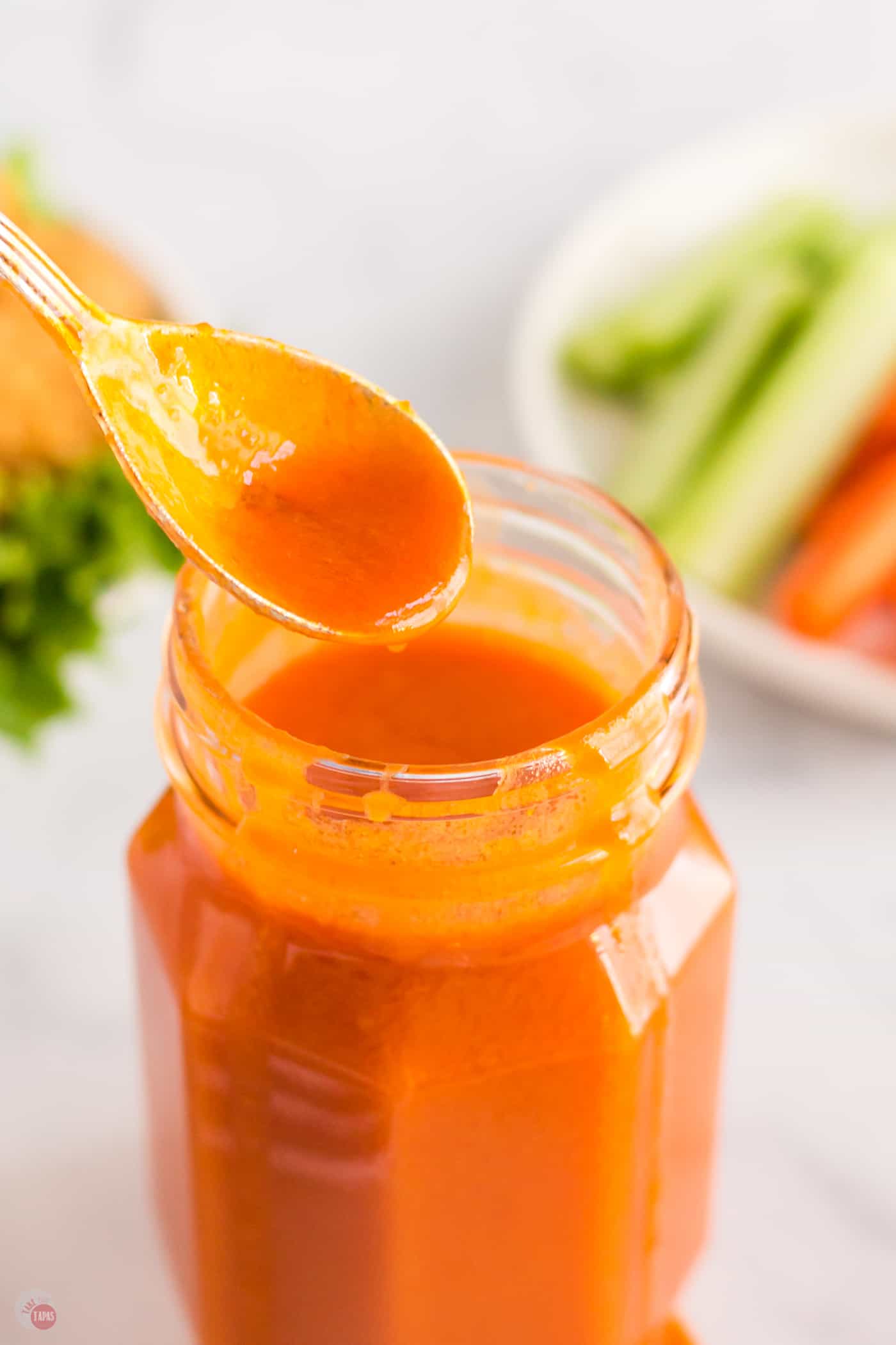 spoon of hot sauce pouring into a jar