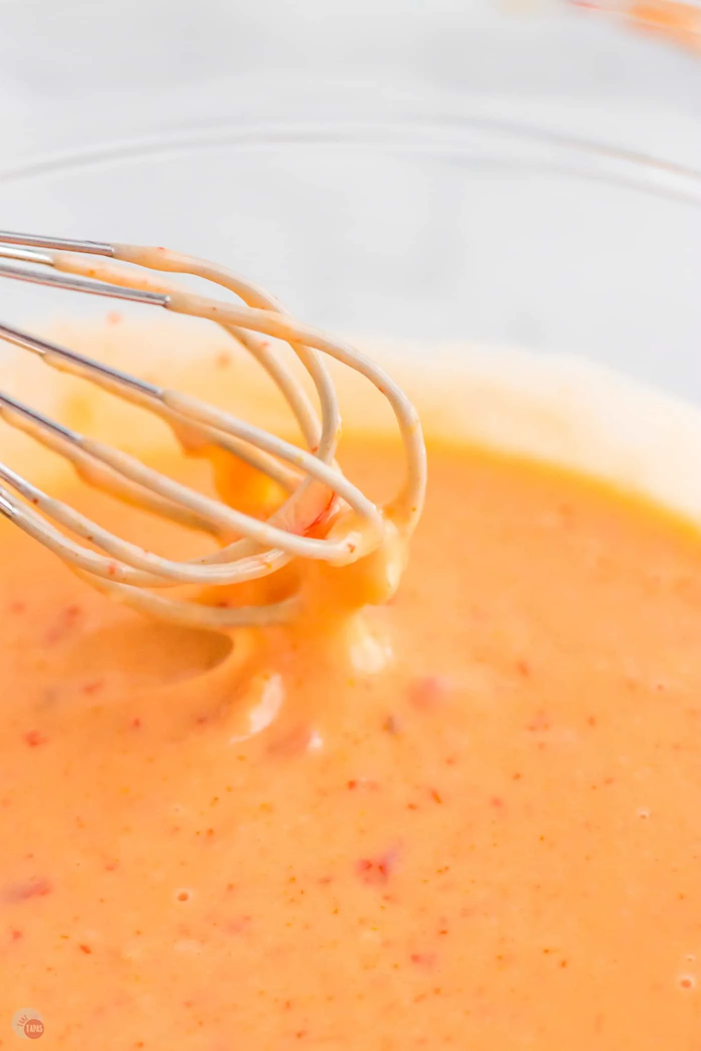 whisk dipping into sauce