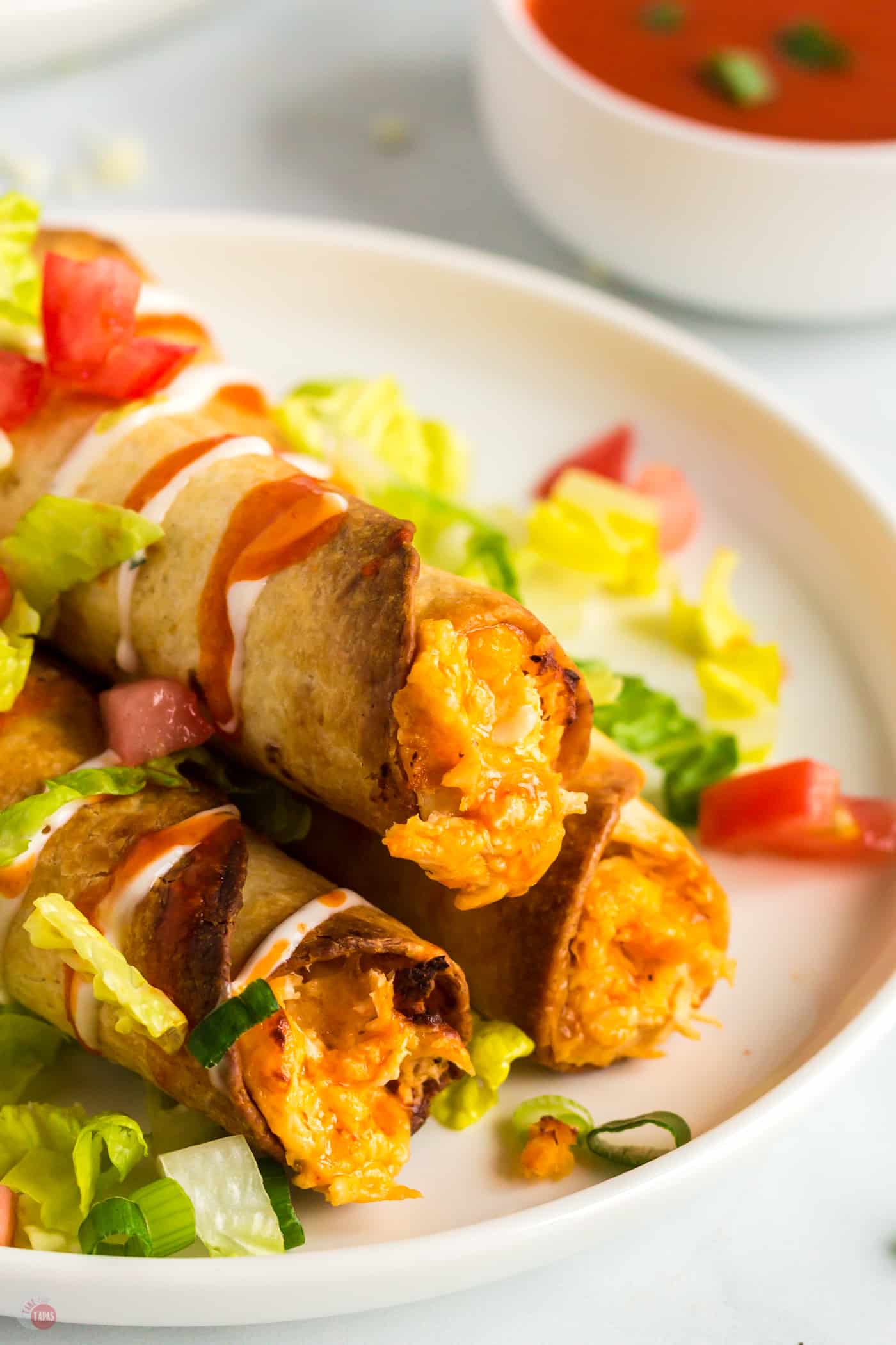 plate with three taquitos and lettuce