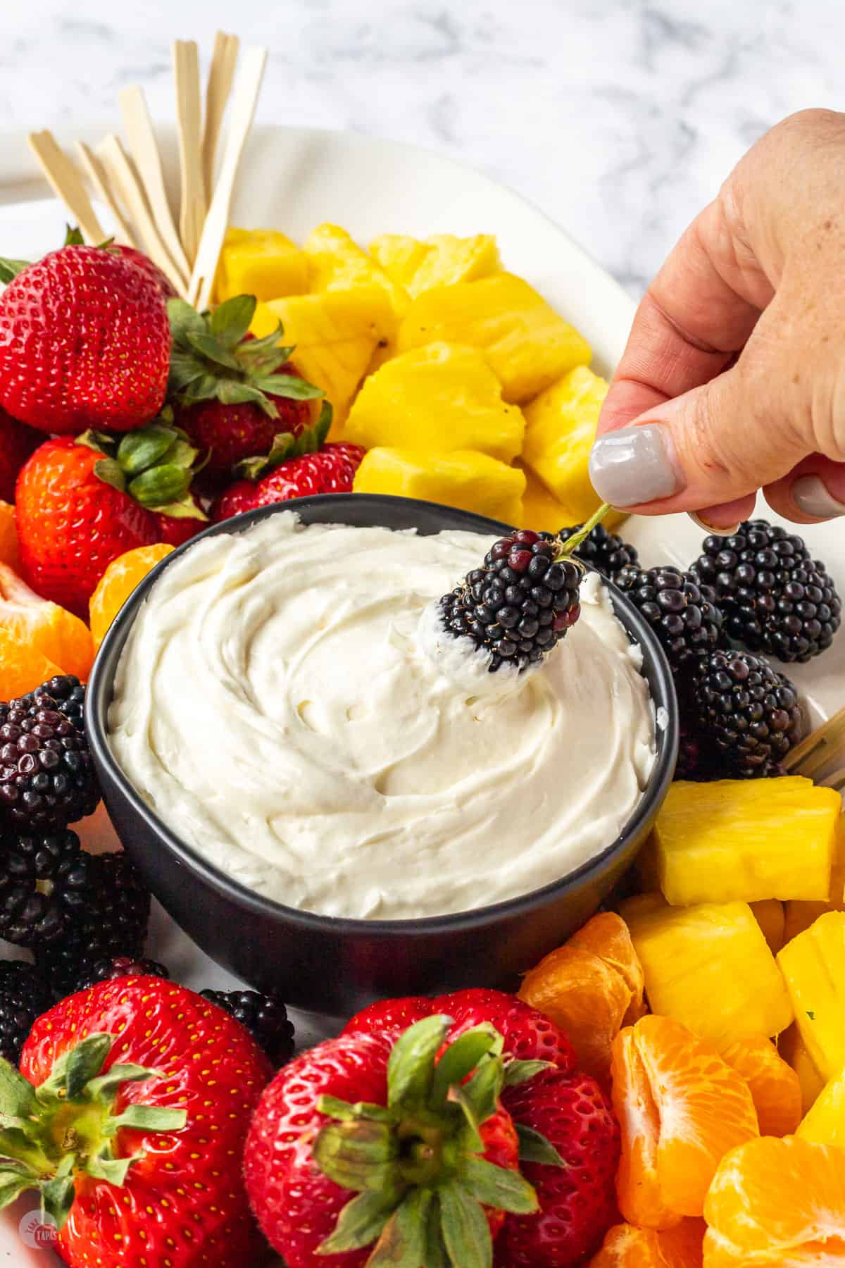 hand holding a blackberry being dipped into marshmallow