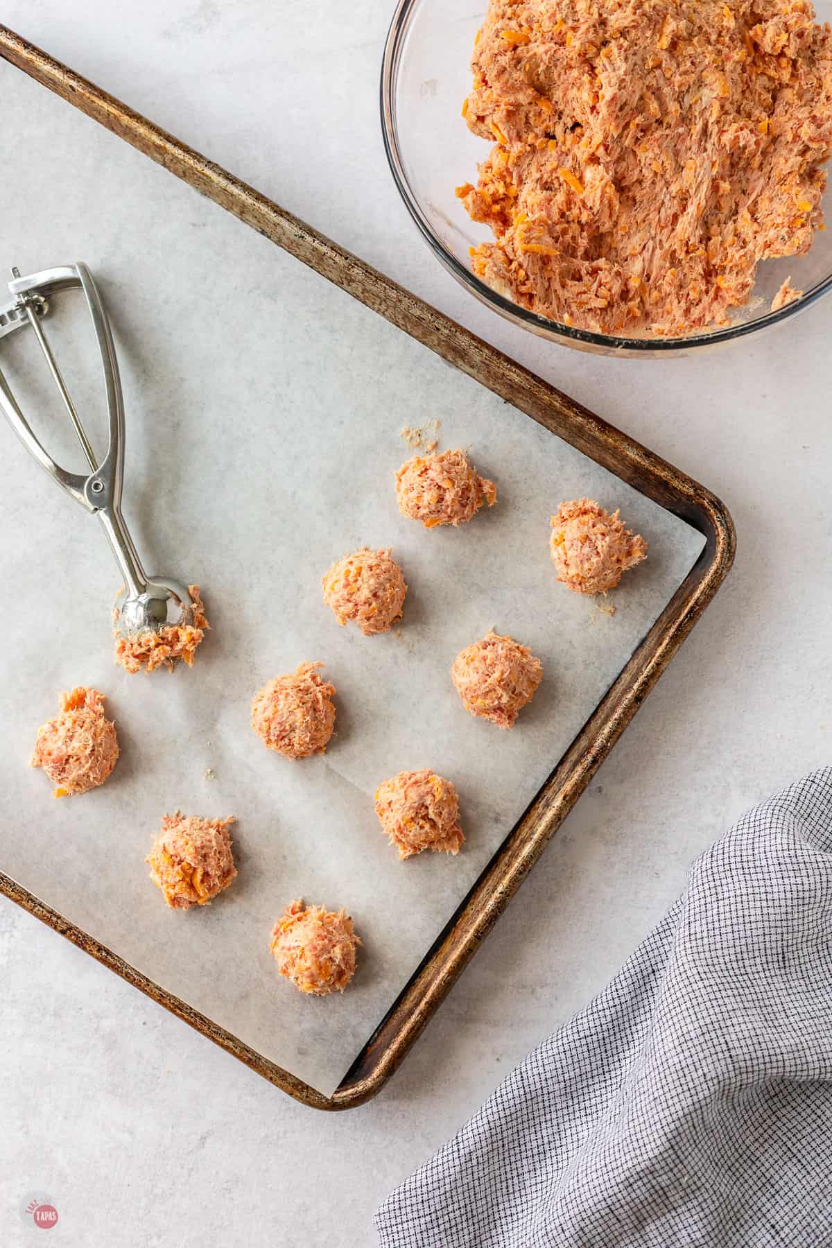 scoops of sausage ball dough on a baking sheet