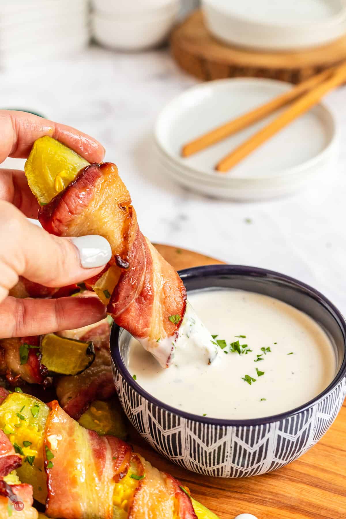 hand holding a pickle with bacon