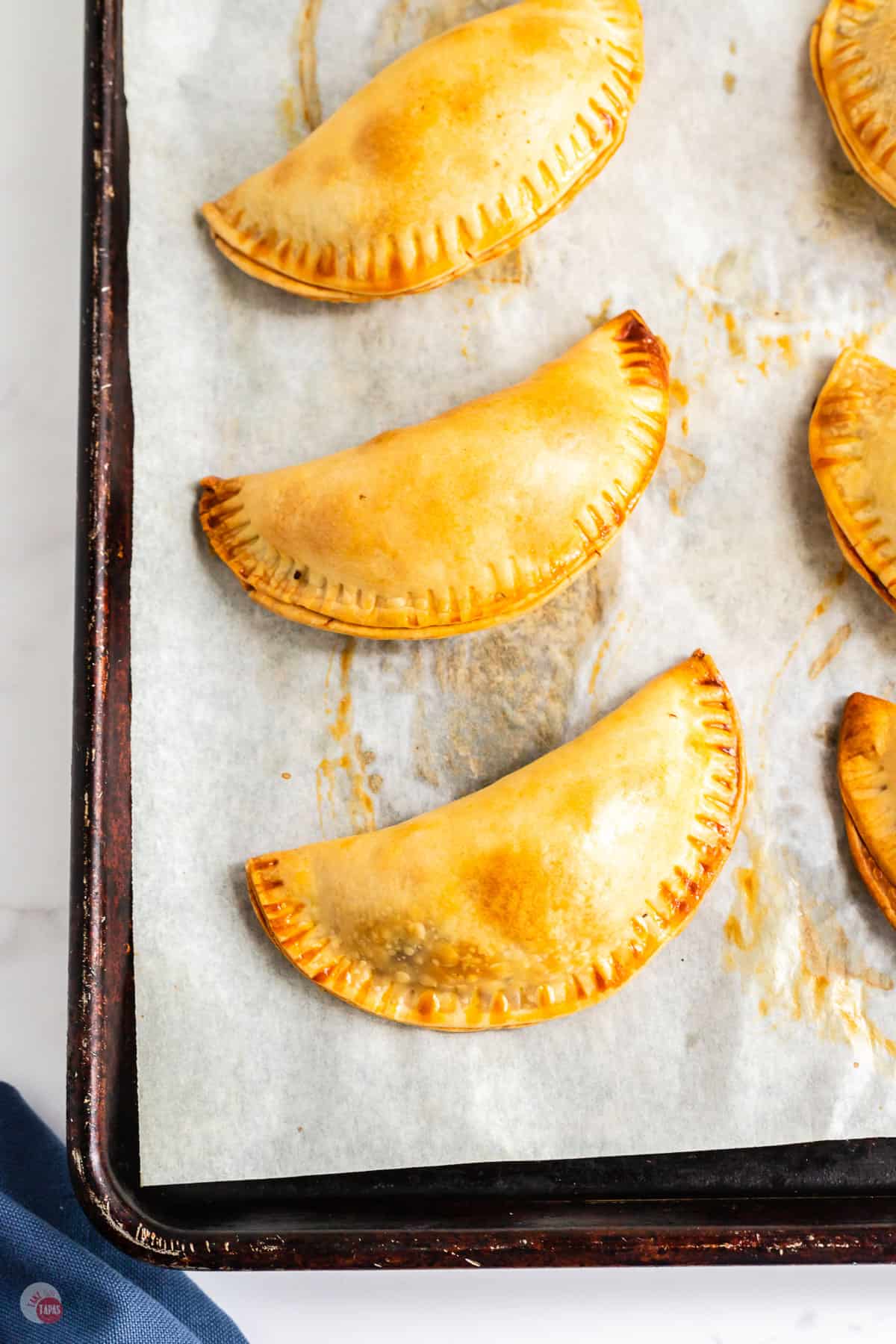 cheesy beef empanadas on a baking sheet