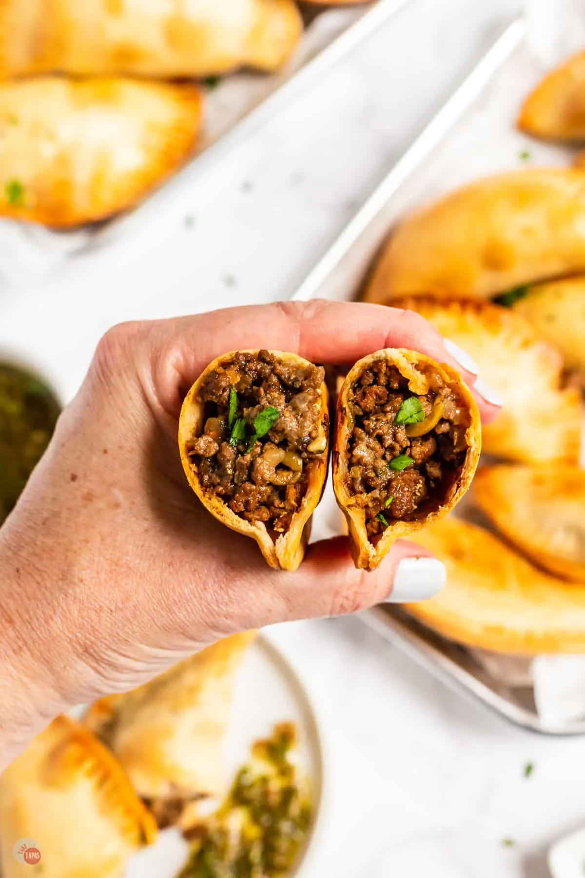 hand holding beef and cheese empanadas cut open