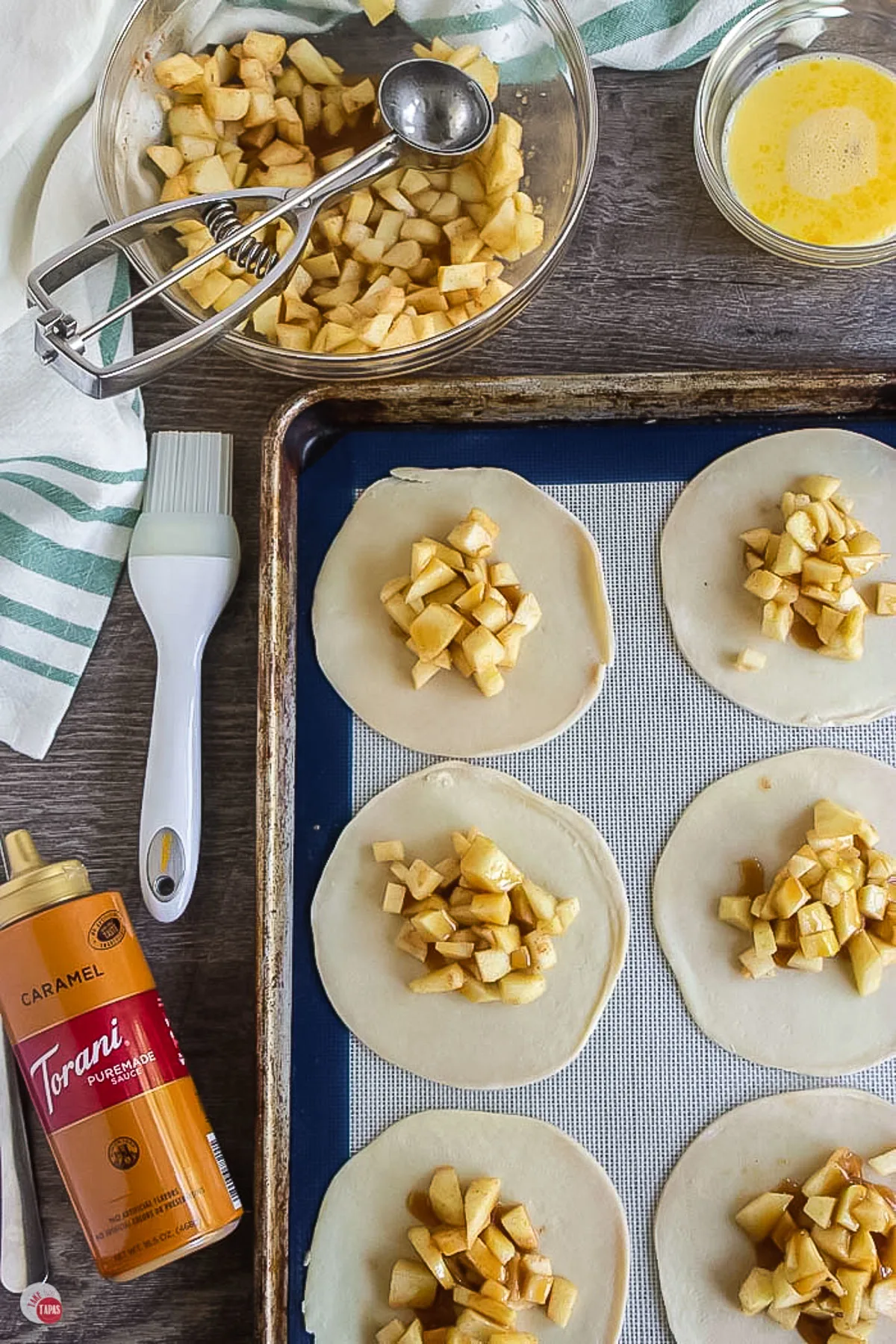 filling on empanada dough rounds on a baking sheet