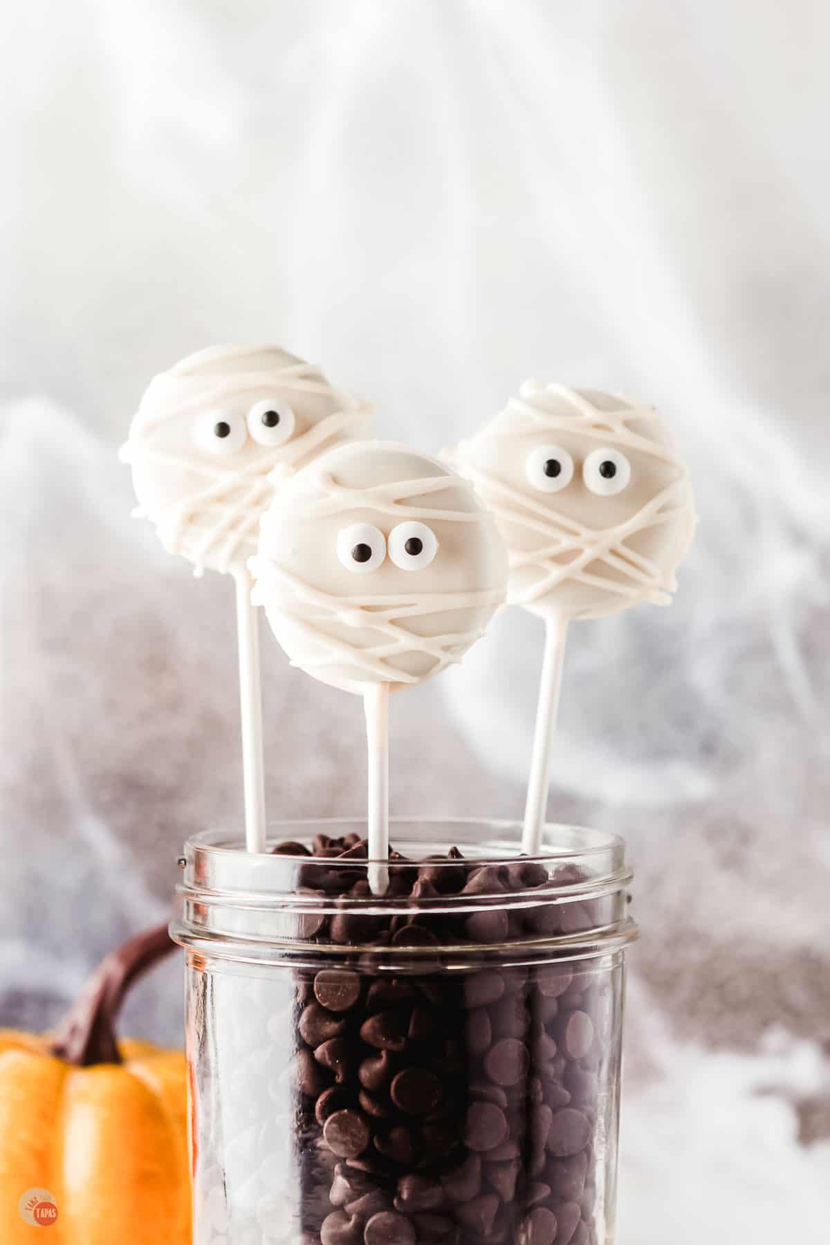 jar with coffee beans with oreo pops decorated like mummies