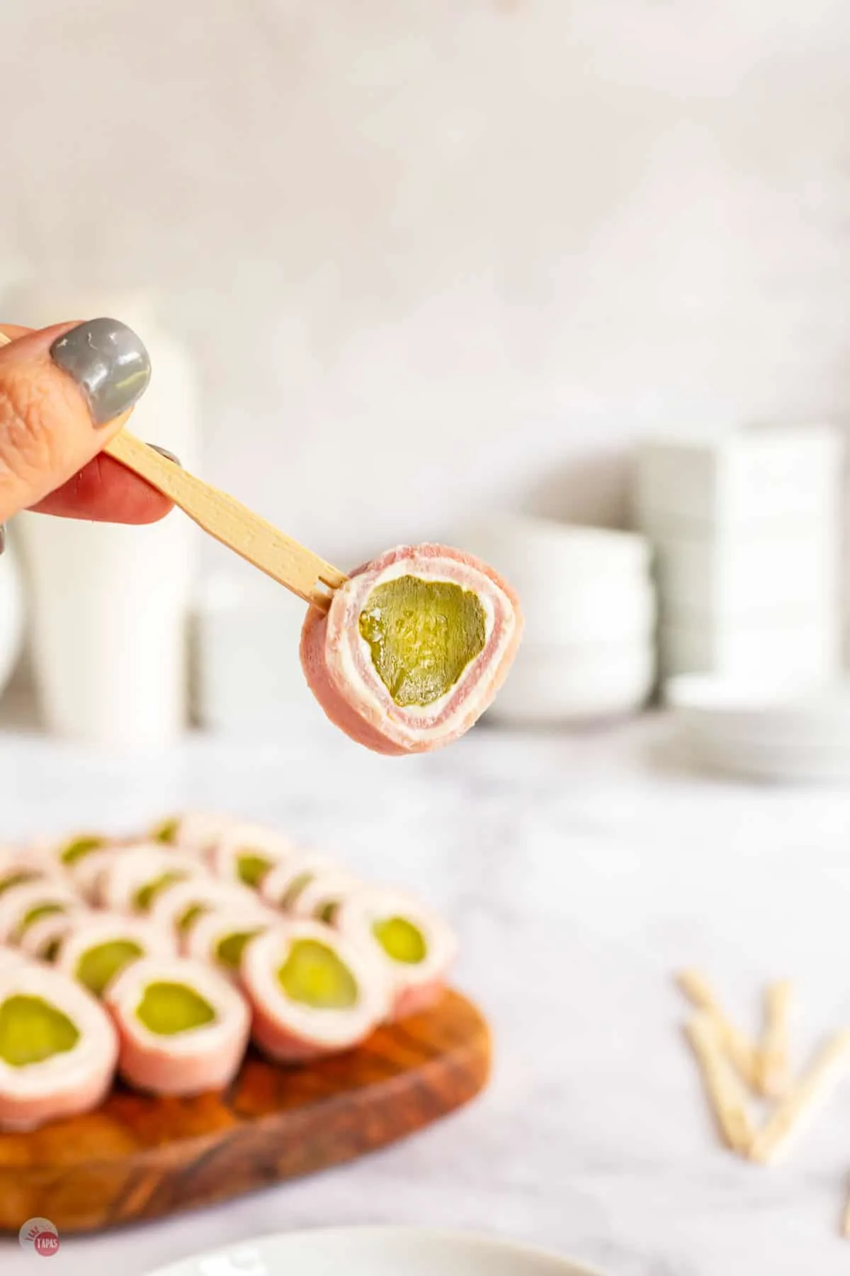 hand holding a toothpick with ham and pickle