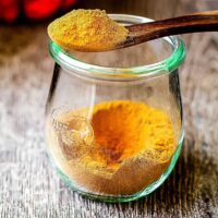 Side view of Pumpkin Pie spice in jar with spoon on top filled with the spice