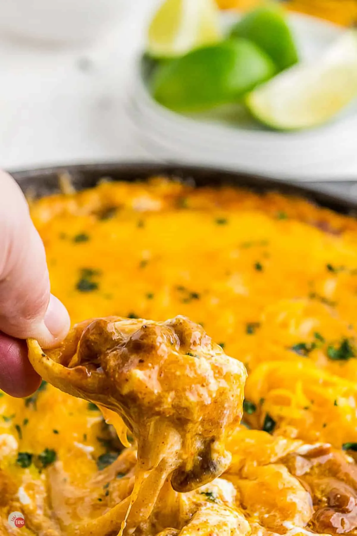 chili cheese dip being scooped out of a skillet