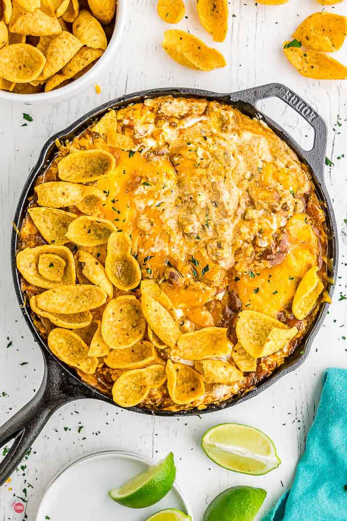 frito pie dip in a black skillet with limes