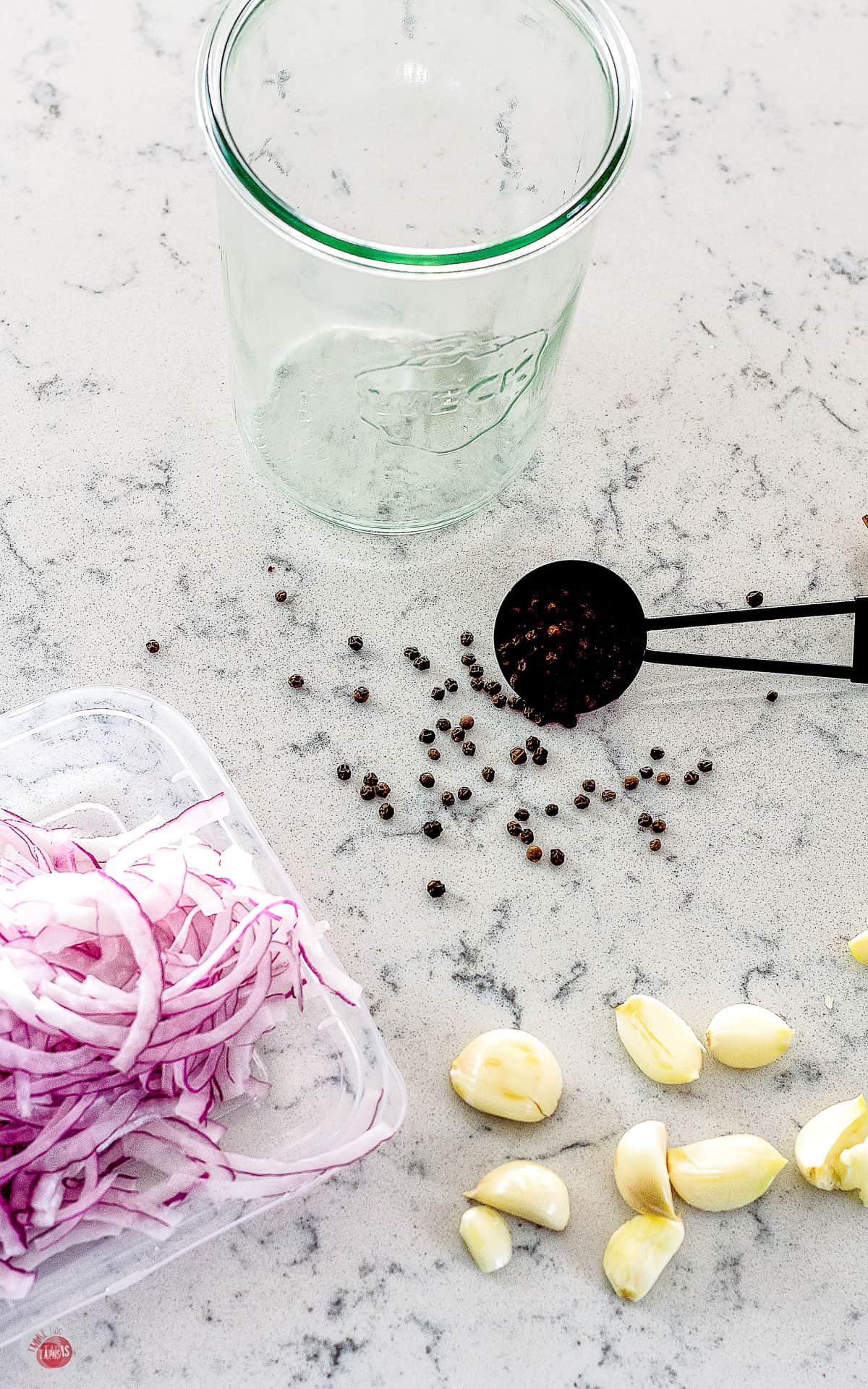 overhead shot of sliced onions garlic cloves and peppercorns on a counter