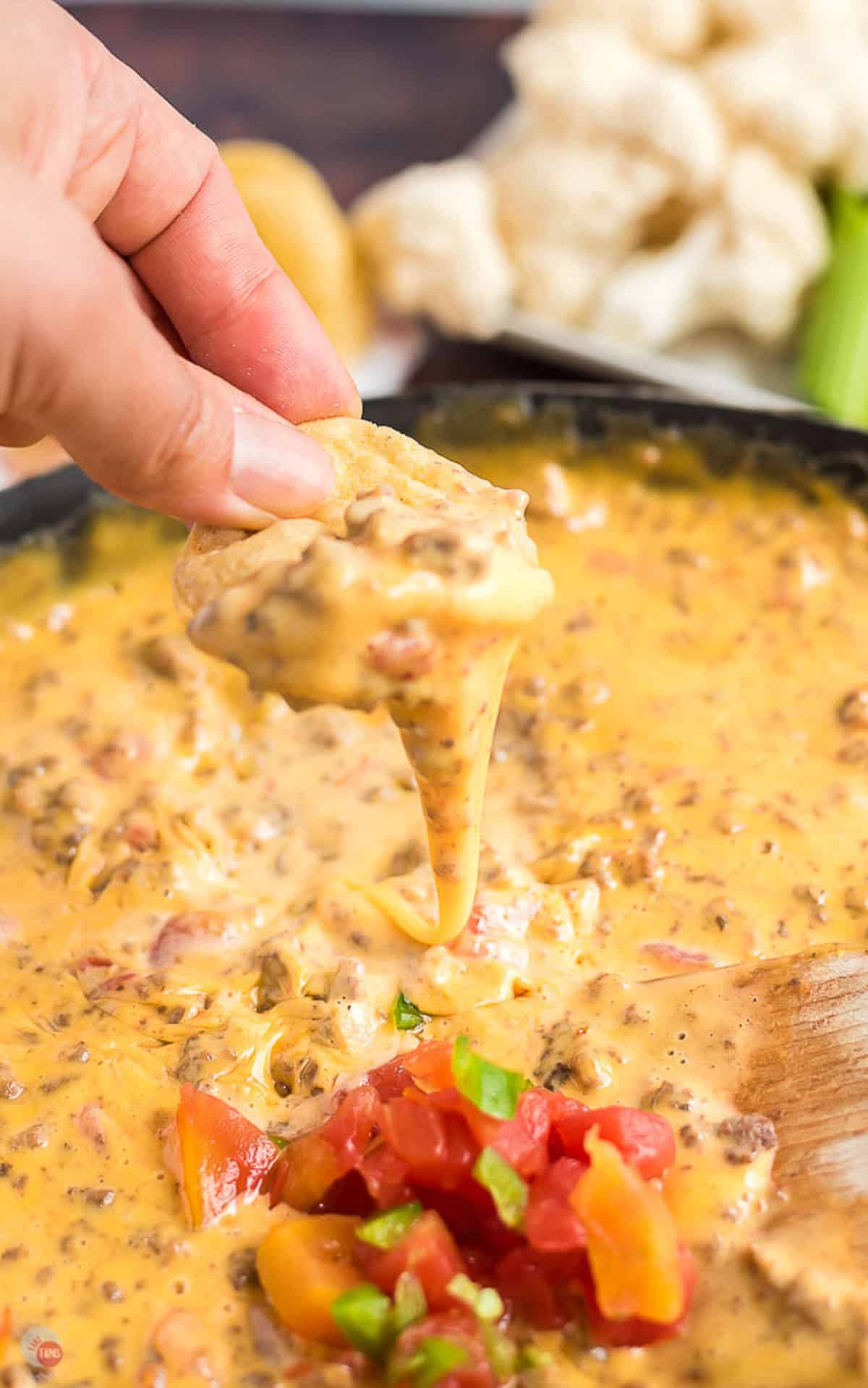 close up of hand with chip dipping out rotel dip