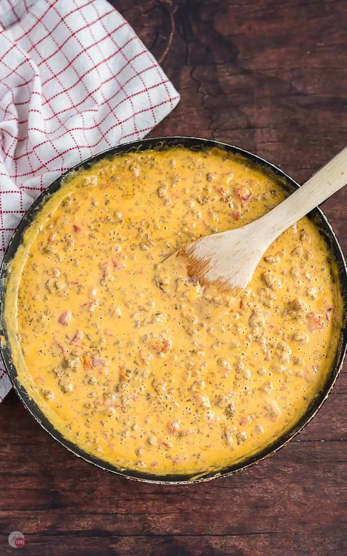 overhead picture of cheese dip in a pan with spatula in it and a napkin on the side