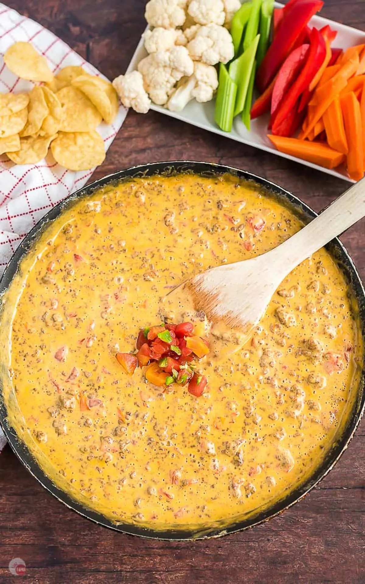 overhead picture of cheese dip topped with salsa in a pan with spatula in it and a napkin on the side and a tray of veggies