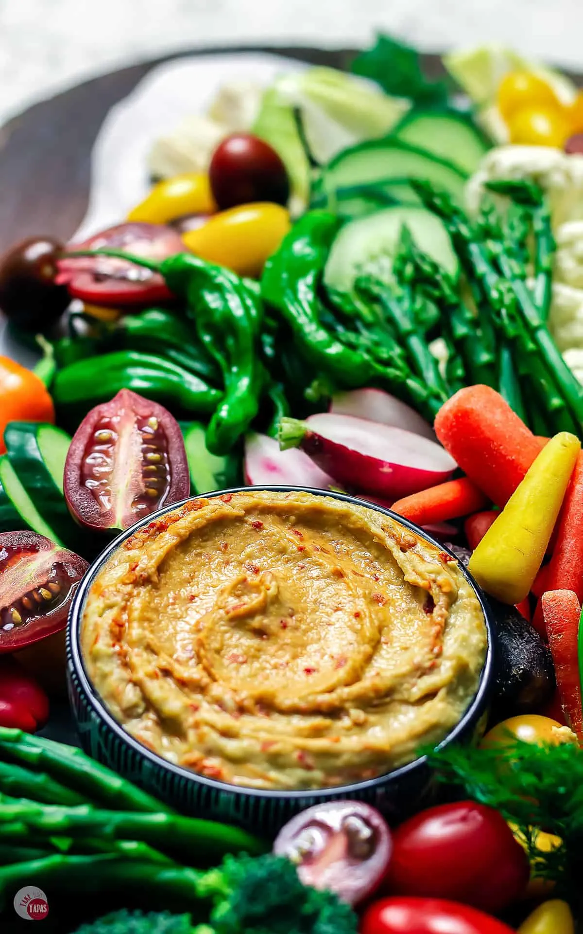 close up of hummus in a bowl on crudite platter
