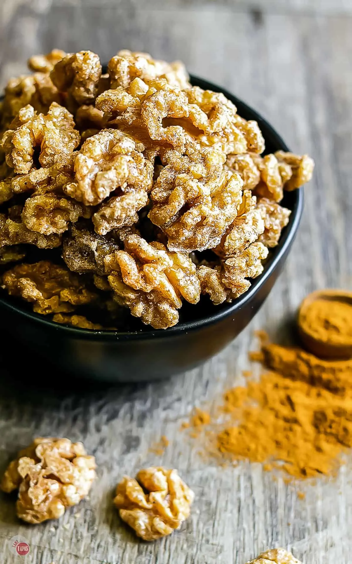 closeup of sugared walnuts in a black bowl