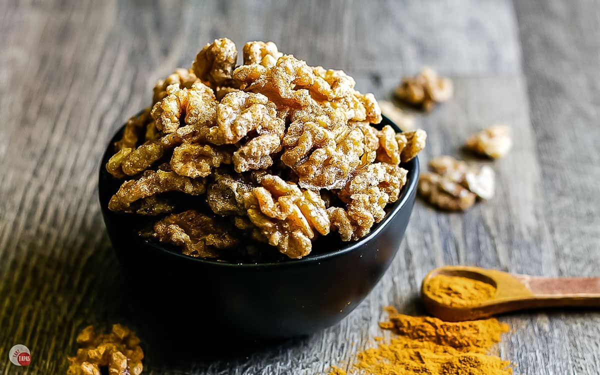 side view of black bowl full of fall spiced walnuts