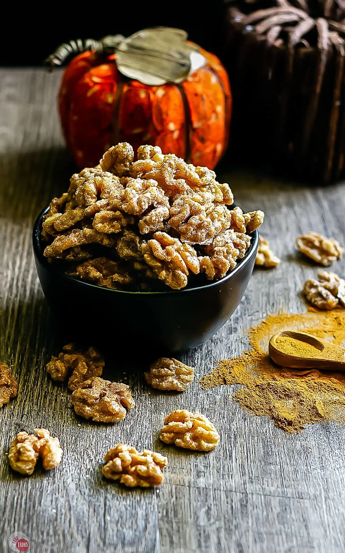 side view of fall spiced walnuts in a black bowl