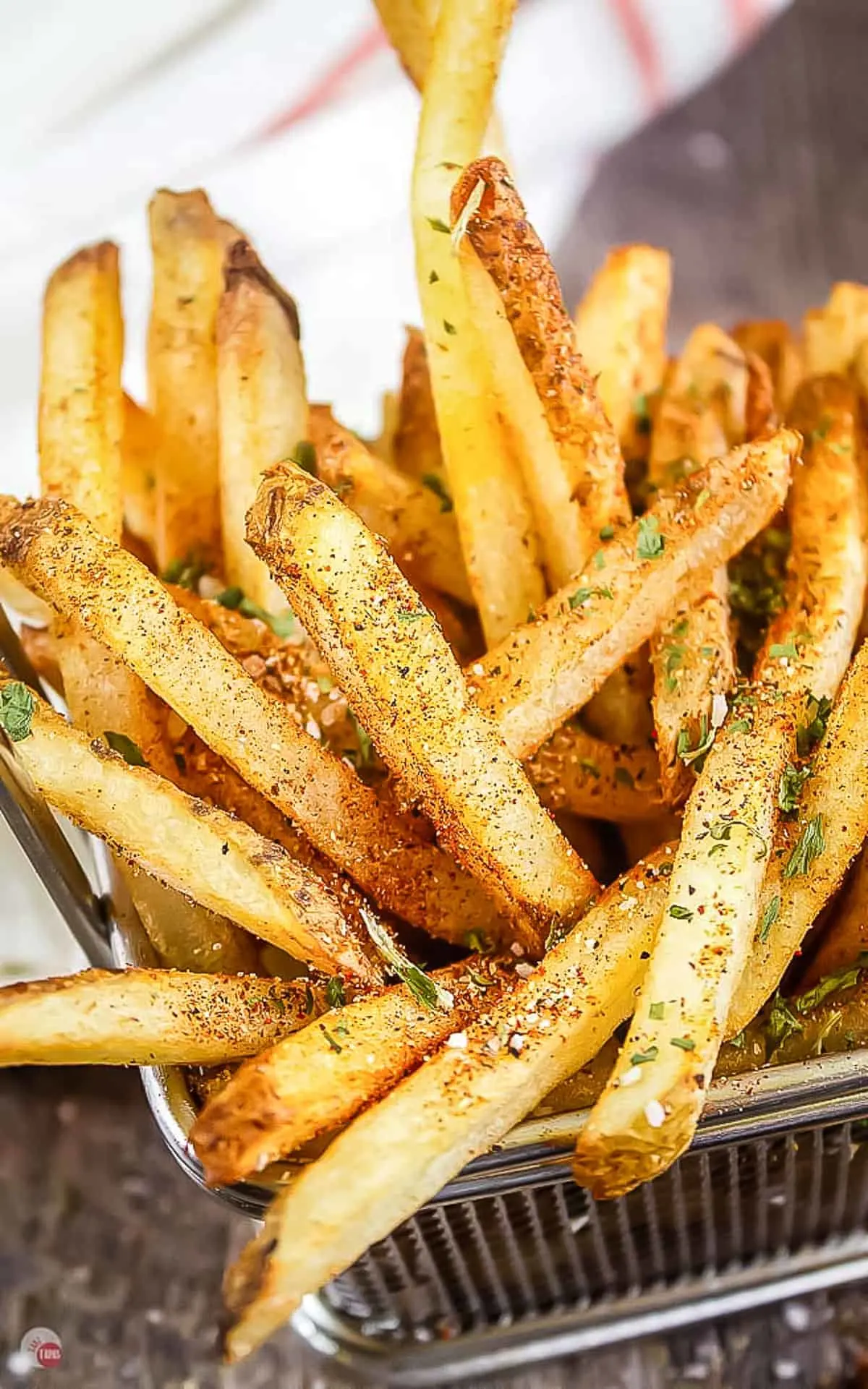 wire basket of fries with seasoning on them