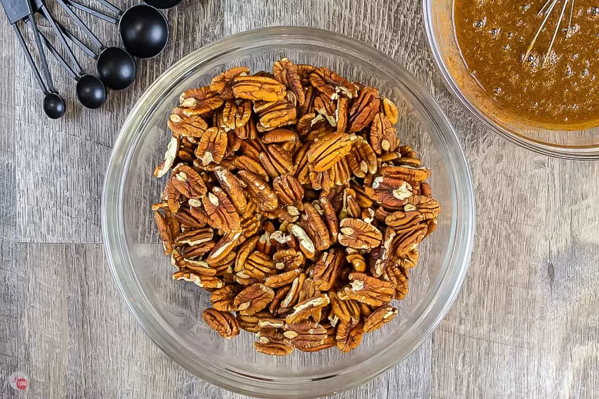 pecans in clear bowl with bowl of sauce and measuring spoons