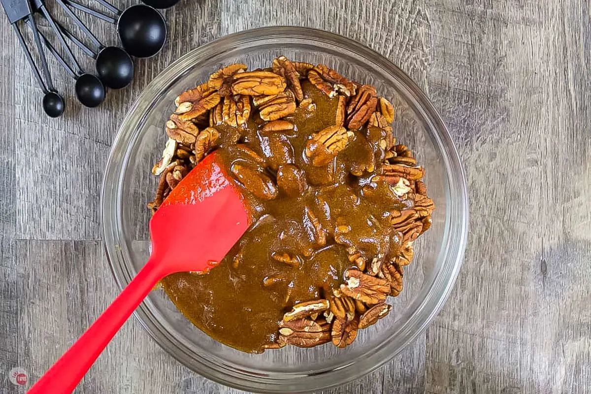 pecans and sauce in a bowl with a red spatula