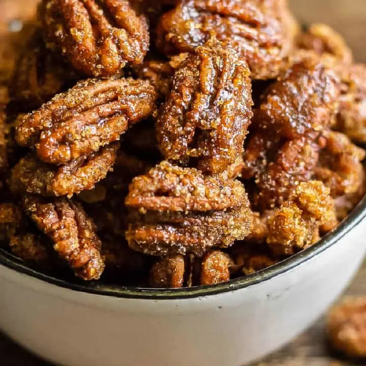 square photo of candied pecans in a white bowl for recipe card