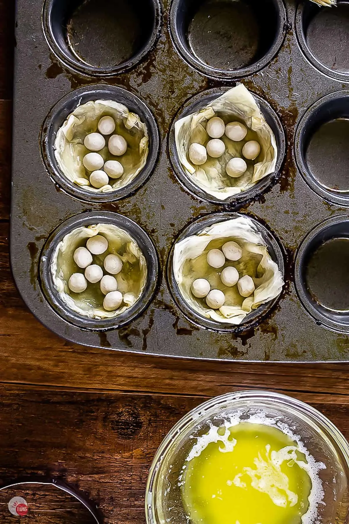 overhead picture of phyllo cups in a mini muffin pan with pie weights in them