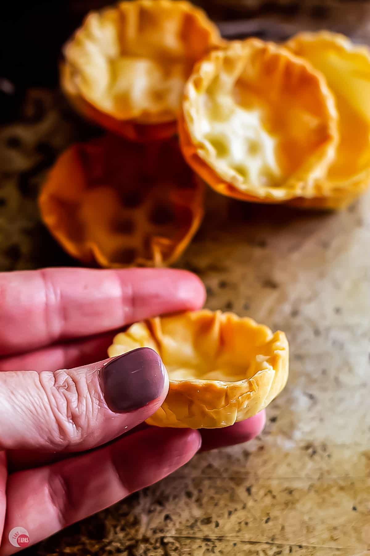 hand holding a round pastry cups