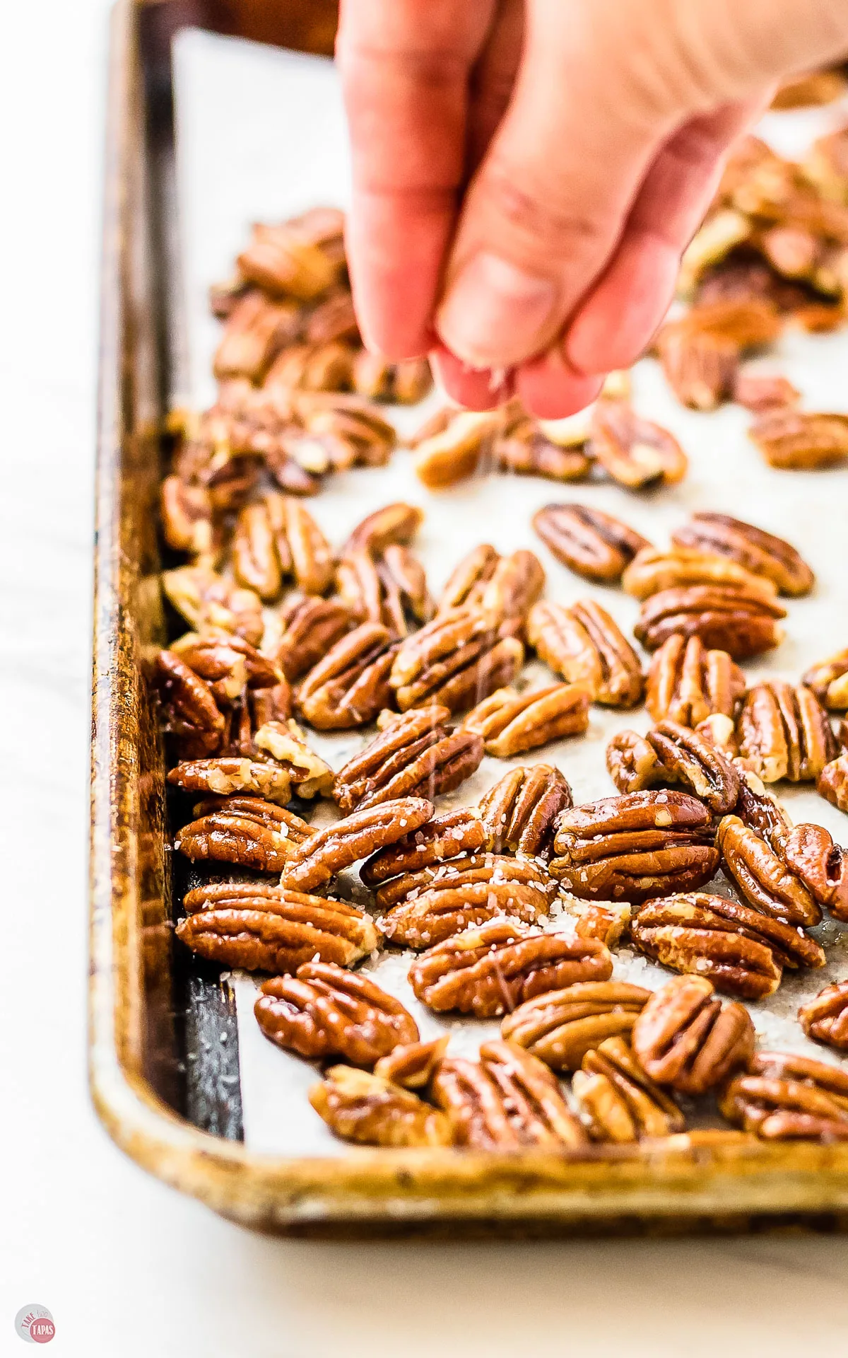 baking sheet of toasted pecans with salt