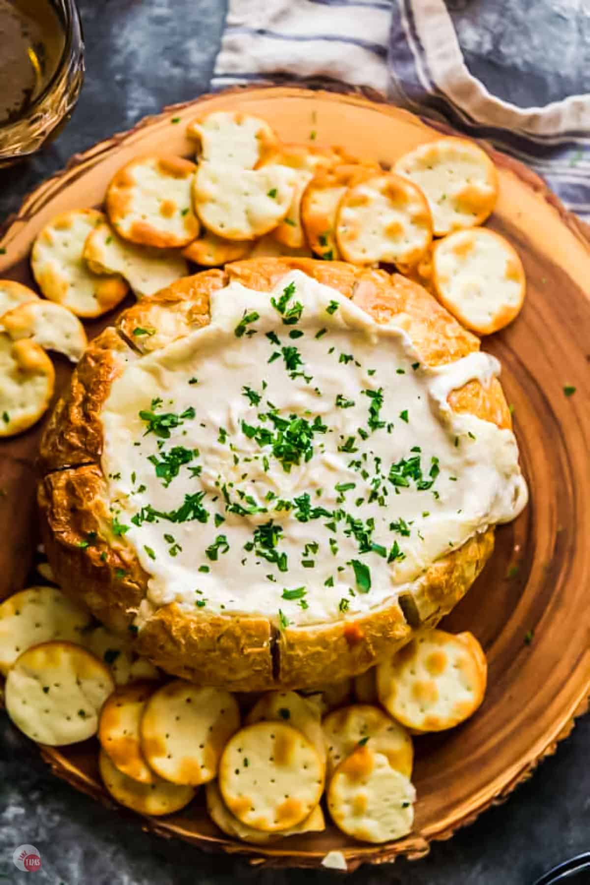 Creamy Beer Cheese Dip in a bread bowl on a serving platter with extra dipping crackers.