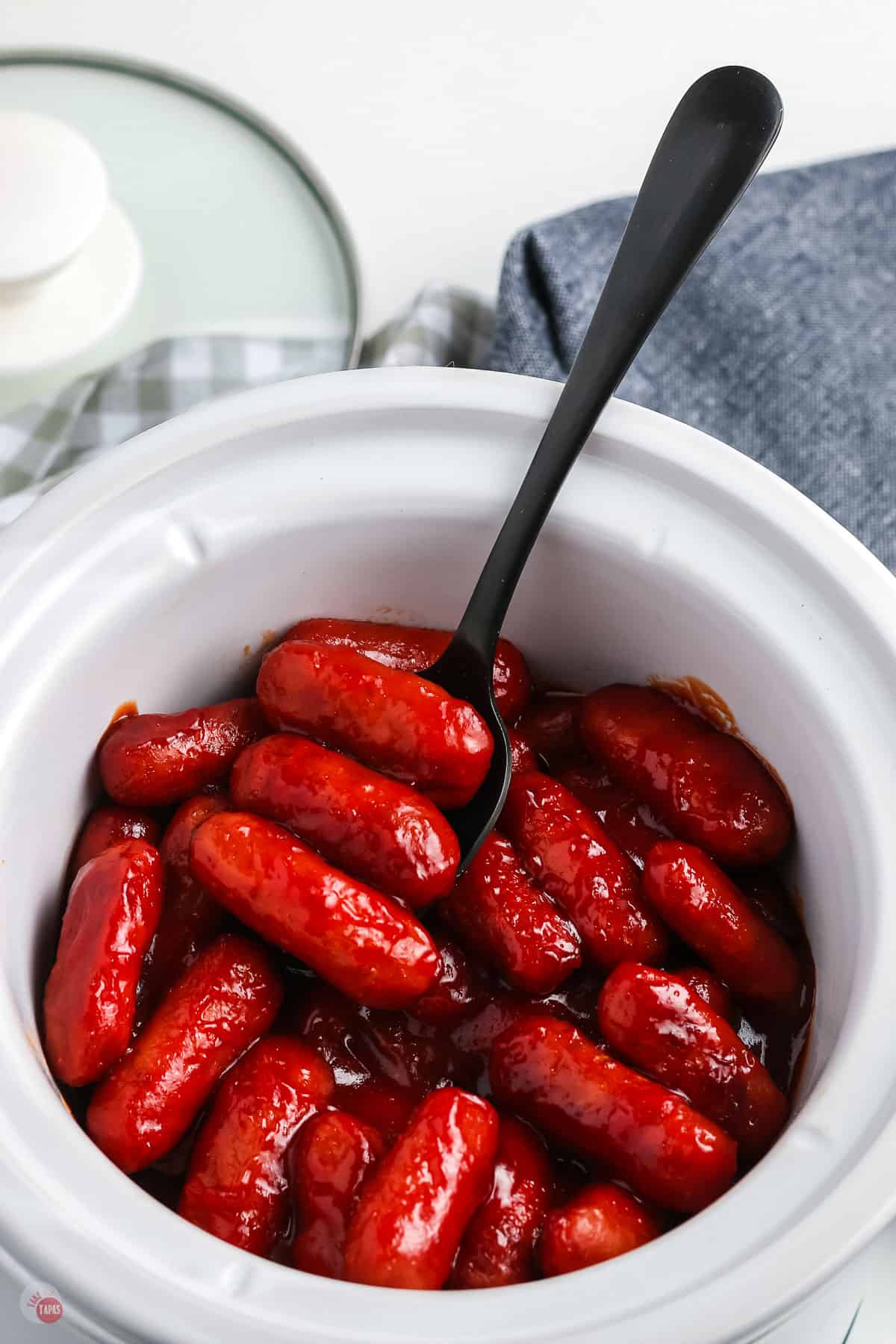little smokies in a white pot with a black fork