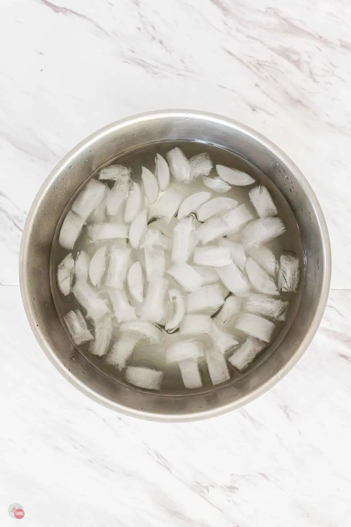 metal bowl full of ice and water on a marble background